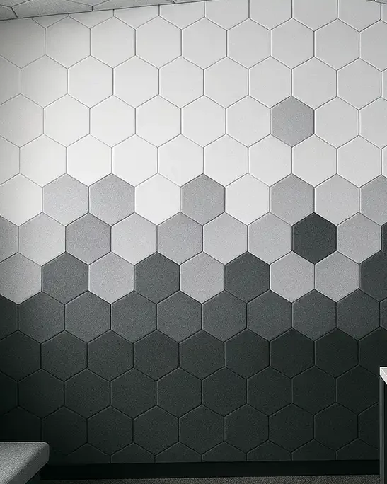 Wall of hexagonal acoustic panels shading from white at the top to charcoal at the bottom