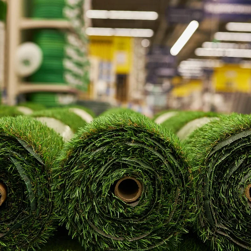 Several rolls of green artificial grass lined up on a showroom floor