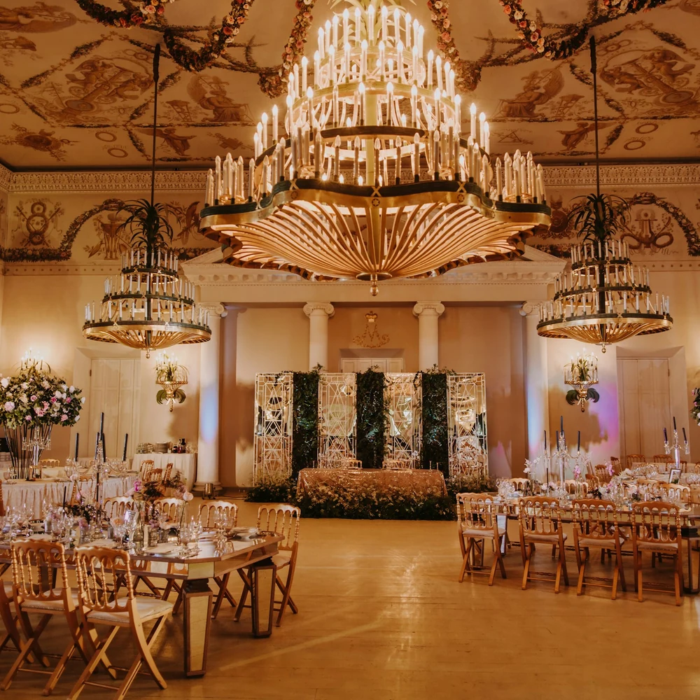 Wedding reception hall with floral stage décor, crystal chandeliers and round tables