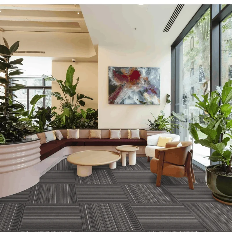 Reception area with a curved bench, large planters and a coffee table on dark grey striped carpet tiles