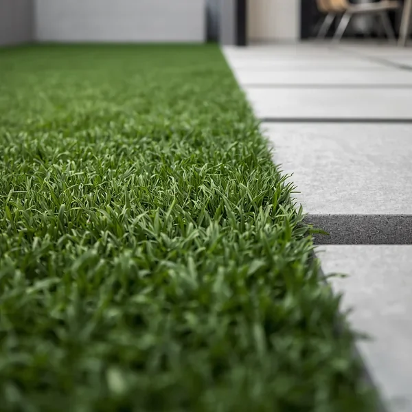 Low close-up of green artificial grass beside pale paving