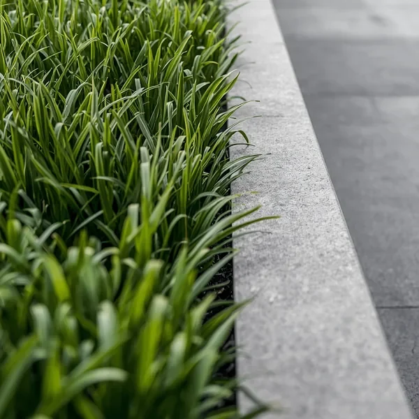 Tall dense artificial grass beside a grey stone edge