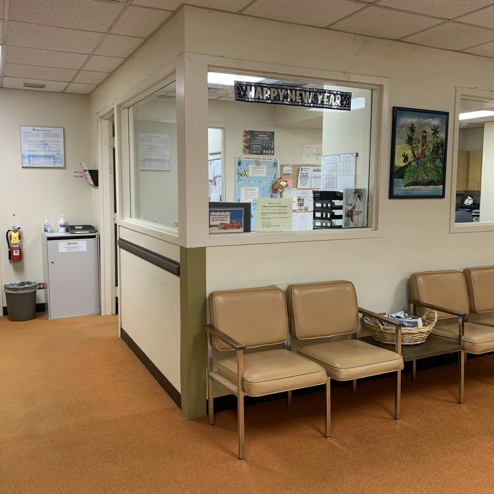 Clinic reception window with a glazed counter and beige waiting chairs along the wall