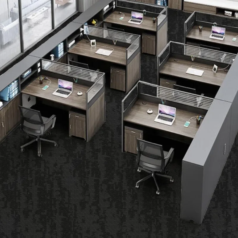 Rows of workstations with grey partitions and laptops on a dark grey carpet tile floor