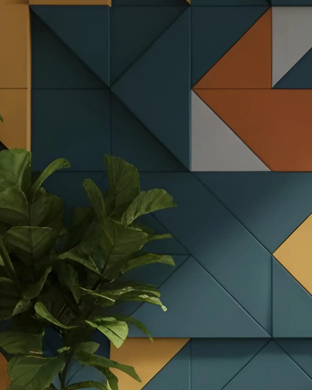 Wall of teal, mustard, orange and grey geometric acoustic panels with a leafy plant in front
