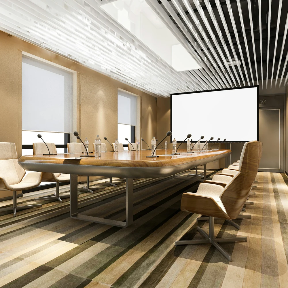 Long boardroom with a timber table, white leather chairs, a slatted ceiling and striped carpet in brown and cream tones