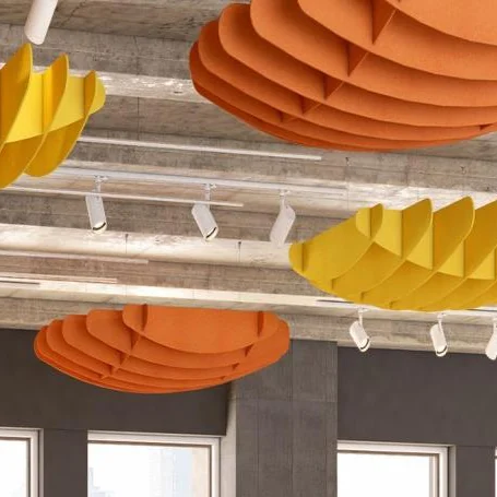 Sculpted acoustic ceiling elements in orange and yellow layered shapes beneath an exposed ceiling with track lights