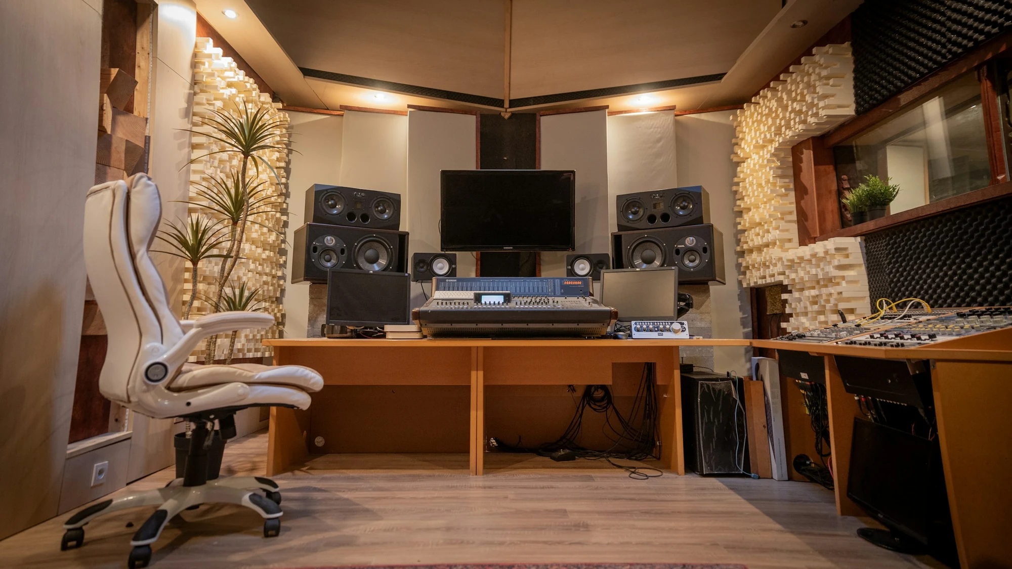 Recording studio with a mixing desk, studio monitors and textured acoustic treatment on the walls and ceiling