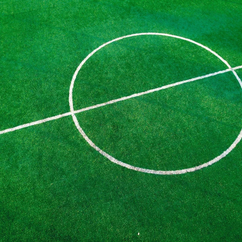 Bright green artificial football turf with a white centre circle and halfway line